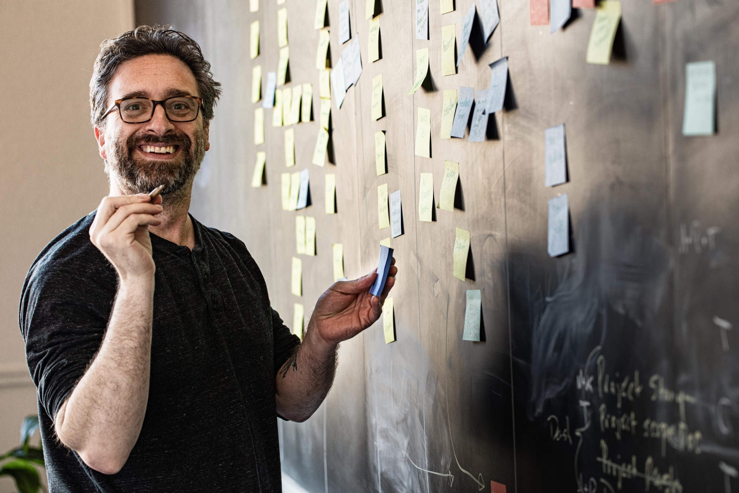 Chris Bolton standing in front of a board with sticky notes, doing web strategy work in a Portland office
